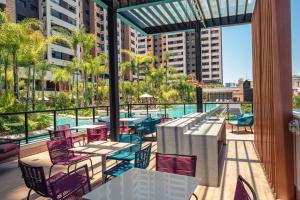 uma varanda com mesas e cadeiras e uma piscina em Incrível resort paradisíaco! em São Paulo