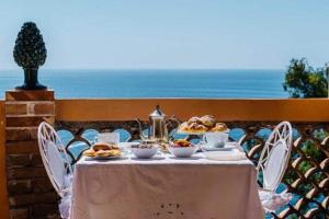 una mesa con comida en ella con el océano en el fondo en B&B La Bergerie, en Taormina