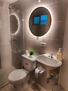a bathroom with a toilet and a sink and a mirror at Exclusivo Apto lujoso central, sereno y cómodo in Medellín