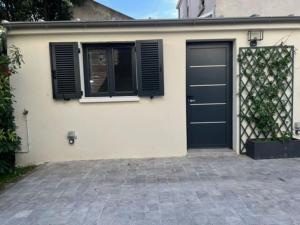 un garage con una porta nera e una finestra di Studio neuf s/jardin, très calme a Colombes