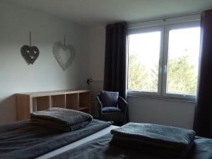 a bedroom with two beds and a window and a chair at Bergblick in Thale