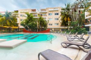 Una piscina con tumbonas frente a un edificio. en The Restful Elephant @ Sabbia D409, en Playa del Carmen