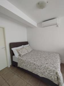 a bedroom with a bed and a white wall at Apartments with sea view Drvenik Makarska riviera in Drvenik