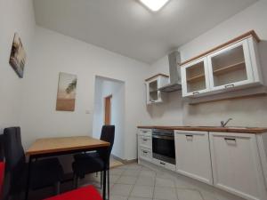 a kitchen with white cabinets and a wooden table at Apartments with sea view Drvenik Makarska riviera in Drvenik