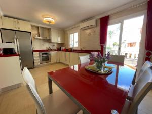 a kitchen with a red table and chairs and a kitchen with at Bungalow on the beach 15 minutes from Valencia in Valencia