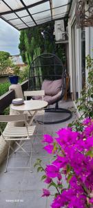 een patio met een tafel, een stoel en paarse bloemen bij Villa 2 pièces Vue Mer Plage à pied in Le Lavandou