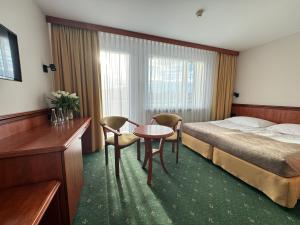 um quarto de hotel com uma cama, uma mesa e cadeiras em Senator em Katowice