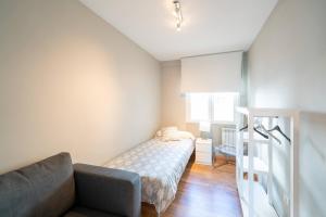 een kleine slaapkamer met een bed en een bank bij Apartamento GO Felipe II Center in Valladolid