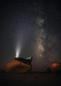 a person sitting on a rock under a starry sky at Wadi Rum Meteor camp in Wadi Rum
