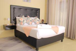 a bedroom with a large bed with a black headboard at Kunzi B&B in Gaborone