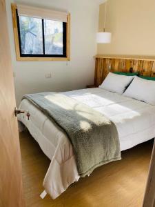 1 dormitorio con 1 cama blanca grande y ventana en Cabaña céntrica en Temuco, en Temuco