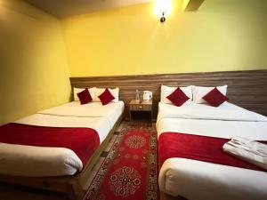 Cette chambre d'hôtel comprend 2 lits avec des oreillers rouges. dans l'établissement Hotel Janani Pvt Ltd, à Pokhara