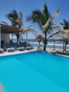 a swimming pool with palm trees and the beach at Las Fragatas Casa Hotel Eventos para 40 personas in Canoas de Punta Sal