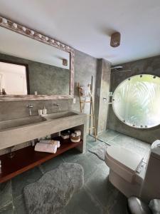 a bathroom with a sink and a mirror and a toilet at La Réserve Villa REPOUSO PARAISO in Pipa