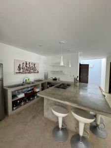 a kitchen with a large counter and two stools at La Réserve Villa REPOUSO PARAISO in Pipa