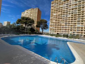 a large swimming pool in front of a tall building at Bungalow on the beach 15 minutes from Valencia in Valencia