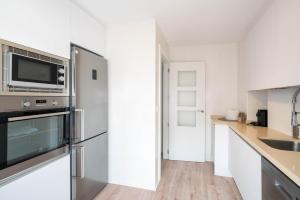 a kitchen with a stainless steel refrigerator and a sink at Apartamentos GO- Chalet Calera, Parking gratuito in Arroyo de la Encomienda