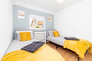 two beds in a small room with yellow sheets at Eastleigh Serviced Apartment in Chandlers Ford