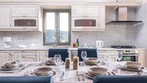 a white kitchen with a table with plates and wine glasses at Villa Ovgoro in Kamilari