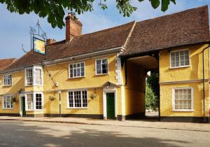 a yellow building with a clock tower on a street at The Tallow Factory in Dedham in Dedham