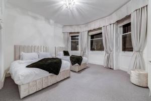 a white bedroom with two beds and windows at Harley Street Spectacular Suites with High Ceilings, High Luxury in London