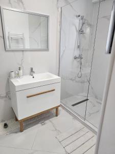 a white bathroom with a sink and a shower at Apartamentul cu amintiri in Mamaia Nord