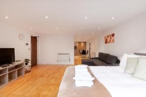 a living room with a large white bed and a couch at Charming Studio Flat in Kingston KT2, London in Kingston upon Thames