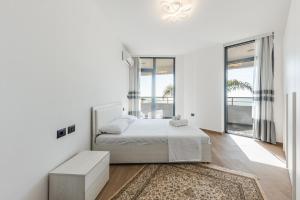 a white bedroom with a bed and a large window at Hill Side Suite by PS in Durrës