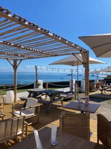 a patio with tables and chairs and umbrellas at Hôtel-Restaurant des Iles in Houat