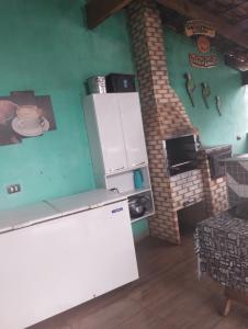 La cuisine est équipée d'un réfrigérateur et d'un four en briques. dans l'établissement Pousada Pôr do Sol, à Uberlândia
