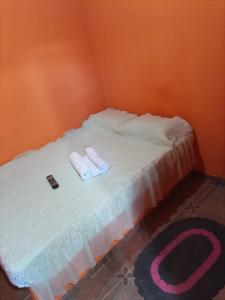 - un lit avec 2 serviettes blanches et une télécommande dans l'établissement Pousada Pôr do Sol, à Uberlândia