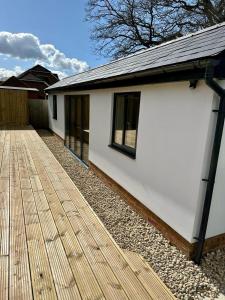 a white house with a wooden deck at White Oaks Sussex in Twineham