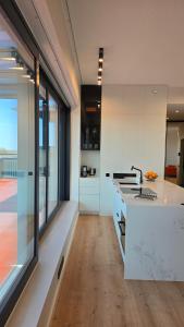 una cucina con banconi bianchi e una grande finestra di Artisa Riia Str 22 Luxury Penthouse Apartment - 8th fl a Tartu