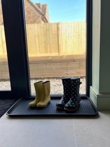 two pairs of rubber boots on a mat in front of a door at White Oaks Sussex in Twineham