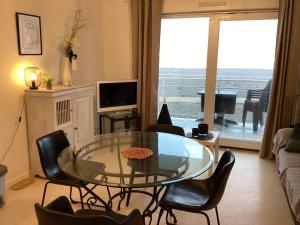 sala de estar con mesa de cristal y sillas en Le Sémaphore, en Cayeux-sur-Mer