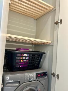 a washing machine in a laundry room with a shelf at White Oaks Sussex in Twineham