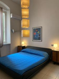 a bedroom with a bed with blue sheets and lights at Appartamento Al Teatro in Livorno