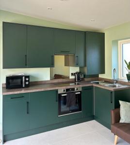 a kitchen with green cabinets and a microwave at White Oaks Sussex in Twineham