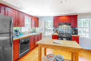 a kitchen with red cabinets and a wooden table at Woods Hole Hideaway in Falmouth