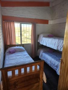 2 Betten in einem Zimmer mit Fenster in der Unterkunft la rosarina in Potrerillos