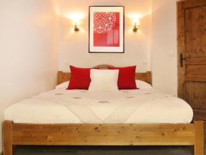 a bedroom with a wooden bed with red pillows at Résidence Les Fermes Du Planet - Pièces 74 in Valloire