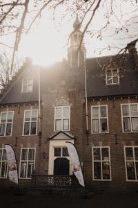 un bâtiment en brique avec une tour d'horloge en haut. dans l'établissement Boutique Hotel het Oude Raadhuis, à Castricum