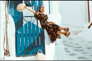 Una donna seduta su un gradino davanti a una porta blu di Eleanna's Mykonos a Mykonos Città