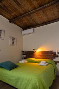 a bedroom with a green bed with a wooden headboard at Filuvespri in Comiso