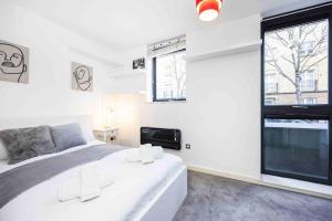 um quarto com uma cama branca e uma grande janela em Stylish 1 BR Apartment Near Shoreditch - 10 Min Walk em Londres
