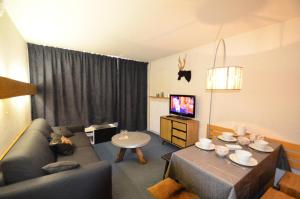 ein Wohnzimmer mit einem Sofa, einem Tisch und einem TV in der Unterkunft Résidence Chaviere - 2 Pièces pour 4 Personnes 434 in Les Menuires