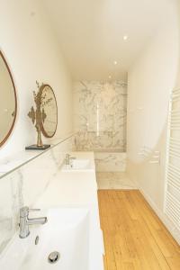 a white bathroom with two sinks and a mirror at Appartement sur les quais in Paris