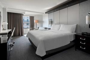 Habitación de hotel con cama blanca grande y escritorio. en JW Marriott Washington, DC en Washington