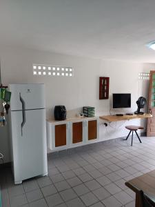 a kitchen with a white refrigerator and a desk at Onda Colorida - Praia de Serrambi CASA 2 - VERDE in Porto De Galinhas