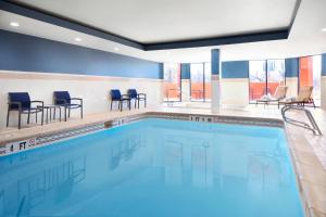 a large swimming pool with chairs and tables at Courtyard Farmington in Farmington